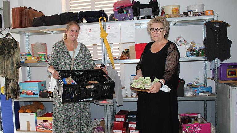 Elke Storch (links, Fachdienst Gemeindecaritas) und Angelika Ochs (Geschäftsführerin Caritasverband) vor dem Gabenregal in Bad Neustadt. Dort können sich Menschen in Not anonym mit Lebensmitteln und Gebrauchsgegenständen versorgen.