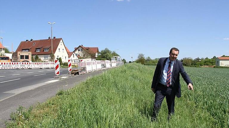 Bis hierher kann künftig geradelt werden: Veitshöchheims Bürgermeister Jürgen Götz zeigt, wie weit das geplante neue Teilstück gehen soll, das den Radweg an der Geithainer Allee verlängert. Das Ganze entsteht in diesem Sommer im Rahmen des Umbaus der Kreuzung Friedenstraße/Günterslebener Straße (im Hintergrund).