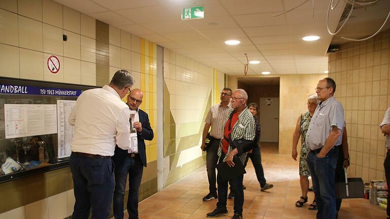 Bauleiter Mustafa Zecic (links) und Bürgermeister Michael Kastl zeigen, wie die Wand im Eingangsbereich aussehen könnte. Die Fliesen sollen eigentlich bleiben, aber es gibt Stellen, wo etwas Neues hin muss. Foto: Thomas Malz       -  Bauleiter Mustafa Zecic (links) und Bürgermeister Michael Kastl zeigen, wie die Wand im Eingangsbereich aussehen könnte. Die Fliesen sollen eigentlich bleiben, aber es gibt Stellen, wo etwas Neues hin muss. Foto: Thomas Malz