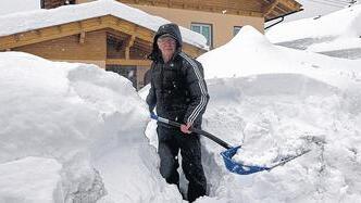 Schippen, schippen, schippen: In Kötschach im Süden von Kärnten gräbt sich ein Mann von seiner Hautür zur Straße durch den Schnee.