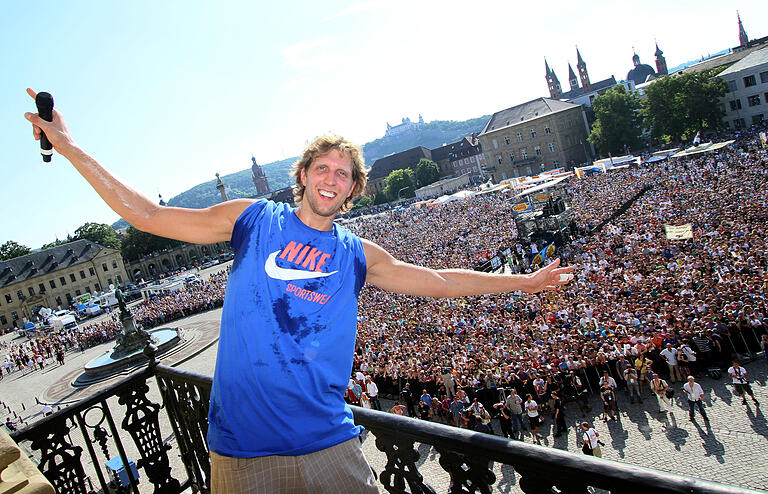 Nowitzki 2011 auf einem Balkon der Residenz in Würzburg, über den Massen, die sich darunter versammelt haben. Rund zwei Wochen nach dem Gewinn des Titels in der nordamerikanischen Basketball-Profiliga NBA wurde er in seiner Heimatstadt von tausenden Menschen auf dem Residenzplatz empfangen.