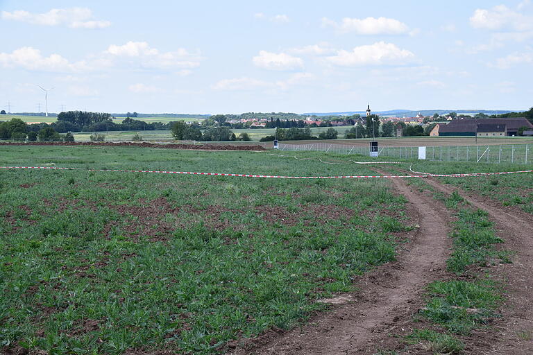 Mit einem Trassenband ist auf der Zehn Hektar-Fläche der Baustelle des SuedLink-Konverters bei Bergrheinfeld die Tabuzone für die Feldlerchen abgegrenzt. Rechts im Hintergrund das Wiesenhaus, dahinter der Ort Ettleben.