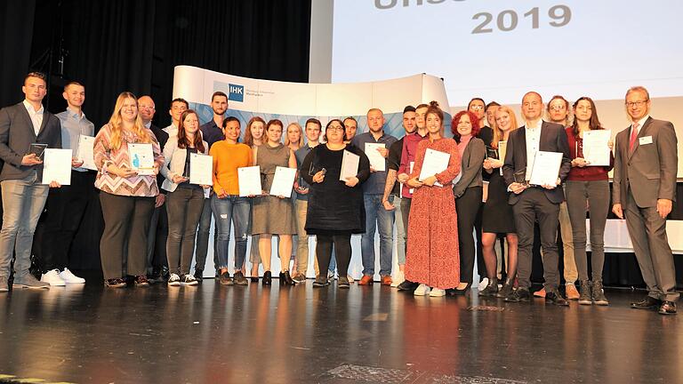 Beim Festakt in der Grafenrheinfelder Kulturhalle würdigten IHK-Präsident Klaus D. Mapara (Vierter von links) und der stellvertretende IHK-Hauptgeschäftsführer Jürgen Bode (rechts) die 30 Prüfungsbesten aus dem Würzburger Raum.