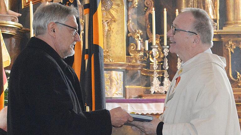 Günter Henneberger (links), einer der Vorsitzenden der Pfarreiengemeinschaft St. Martin, überreichte ein Gratulationsbuch.