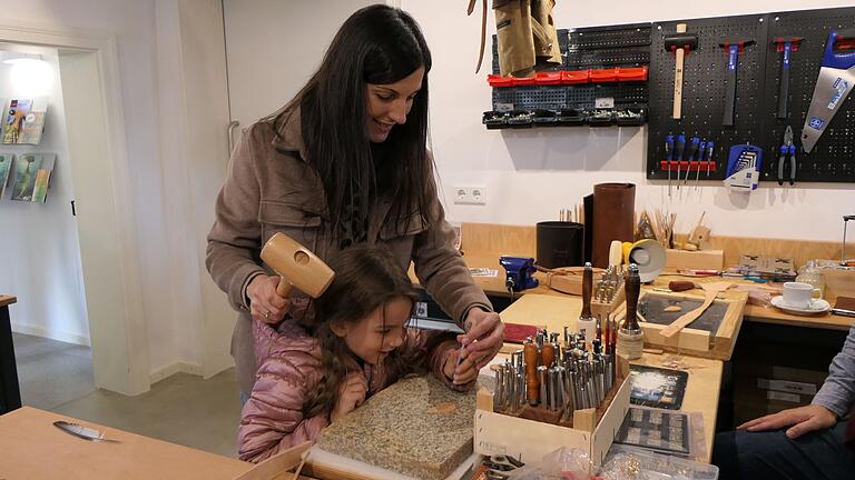 Die sechsjährige Emma suchte sich für ihren selbstgestalteten Anhänger die passenden Punziereisen aus und positionierte sie auf dem Leders, während ihr ihre Mama mit dem Hammer etwas zur Hand ging.