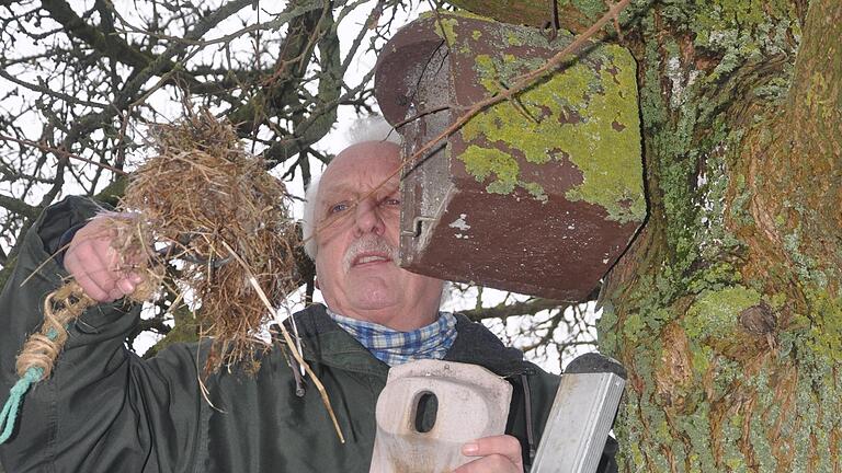 Richard Öchsner beim Reinigen eines Nistkastens. Er hält in der rechten Hand das Nistmaterial und in der linken Hand die herausnehmbare vordere Wand.