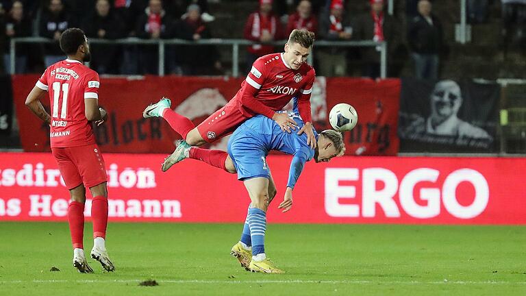 Huckepack-Zweikampf um den Ball: Marius Wegmann (Mitte oben) von den Würzburger Kickers mit einer fast artistisch anmutenden Einlage auf dem Rücken von Illertissens Franz Helmer, der früher selbst das Trikot der Rothosen trug. Links schaut Fabrice Montcheu (Würzburger Kickers) zu.