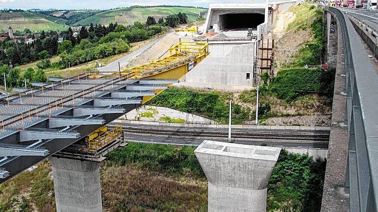 A 3: Die letzten Meter der neuen Talbrücke       -  Am Dienstag geht es los, mit dem letzten Stück des Vorschubes der Nordfahrbahn der neuen Heidingsfelder Talbrücke der A 3. Das Teilstück hat ein Gewicht von 466 Tonnen und eine Länge von 70 Meter, informiert Wolfgang Thaler,  Losbauführer bei der Autobahndirektion Nordbayern.   Damit sind bislang 5321 Tonnen Baustahl verbaut worden, die eine Gesamtlänge von 635 Metern überbrücken. Laut Zeitplan beginnt am Dienstagmorgen der Vorschub. Zunächst werden ca. 20 Meter geschoben; dann steht der sogenannte Vorbauschnabel direkt vor dem Widerlager Nürnberg.   Dort wird bereits am Montag ein Großkran aufgebaut. Dieser übernimmt am Dienstag gegen Mittag die Aufhängelast aus dem Vorbauschnabel, berichtet Thaler. Am Dienstagnachmittag wird dann die vordere Hälfte des Vorbauschnabels abgetrennt, anschließend werden noch am Abend oder am Mittwochmorgen weitere rund 20 Meter geschoben.   Am Mittwochmorgen wird dann die zweite Hälfte des Vorbauschnabels abgebaut und am Mittwochnachmittag wird der auskragende Teil des Stahlüberbaus mit dem Großkran angehängt und in den Endzustand an das Widerlager verschoben. Bis der nördliche Brückenteil dann komplett fertig ist und während des Rückbaues der alten und des Neubaus der südlichen Fahrbahn den Verkehr aufnehmen kann, wird noch ein weiteres Jahre vergehen, so Thaler weiter.   Ab Ende August sollen Fertigteile oben auf den Stahlüberbau gelegt werden, die als Schalung dienen. Auf die gesamte Brückenplatte kommt dann ab etwa Ende September eine durchgehende 30 cm dicke Stahlbetonschicht, auf der dann im Sommer der endgültige Belag aufgebracht werden kann. Foto: Wolfgang Thaler