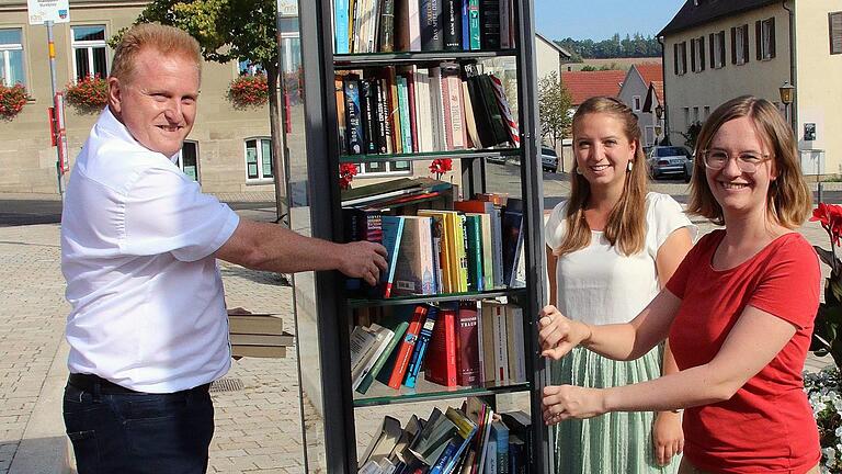 Dieser Bücherschrank steht auf dem Maßbacher Marktplatz. Jeder darf Bücher entnehmen und hineinstellen. Zur Inbetriebnahme kamen Bürgermeister Matthias Klement (links, Allianzmanagerin Hannah-Rabea Grübl (rechts) und ihrer Praktikantin Miriam Mai.  Foto: Dieter Britz       -  Dieser Bücherschrank steht auf dem Maßbacher Marktplatz. Jeder darf Bücher entnehmen und hineinstellen. Zur Inbetriebnahme kamen Bürgermeister Matthias Klement (links, Allianzmanagerin Hannah-Rabea Grübl (rechts) und ihrer Praktikantin Miriam Mai.  Foto: Dieter Britz