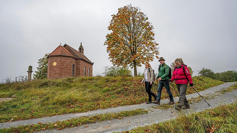 Eine Wandergruppe passiert die Dreifaltigkeitskapelle in Reicholzheim: Die Taubertäler Wandertage bieten geführte Wanderungen zu lokaltypischen Orten und Begebenheiten.