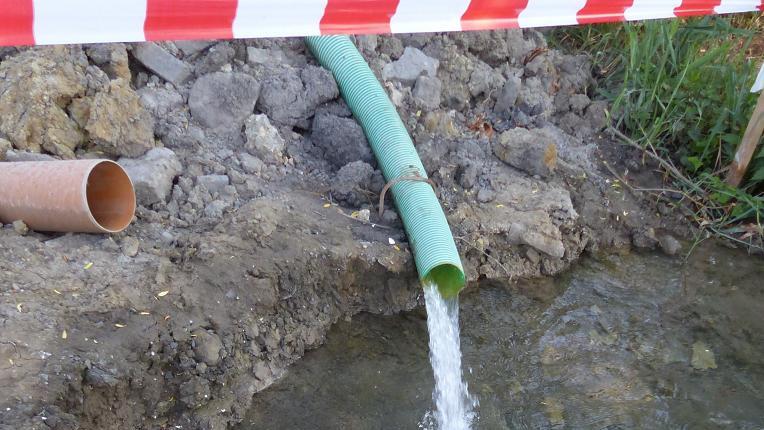 Ständig läuft die Pumpe: Das abgepumpte Wasser aus der Baugrube wird erst in ein Auffangbecken und dann in den benachbarten Bach geleitet.