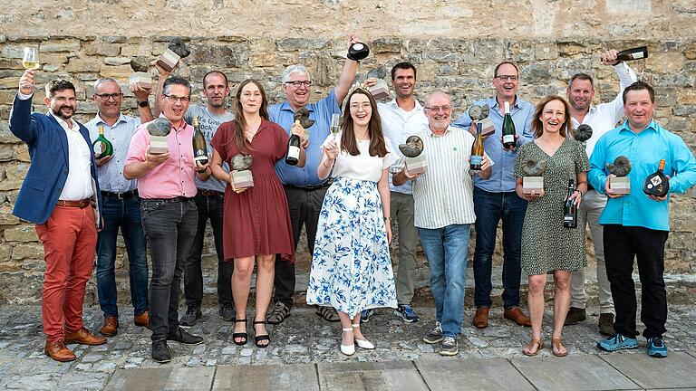 Ralf Schwarz (links) und Weinkönigin Lisa Lehritter (Mitte) präsentieren die elf Sieger im Wettbewerb 'Best of Franken' im Gutshof des Weinguts Zehntkeller in Iphofen.&nbsp;