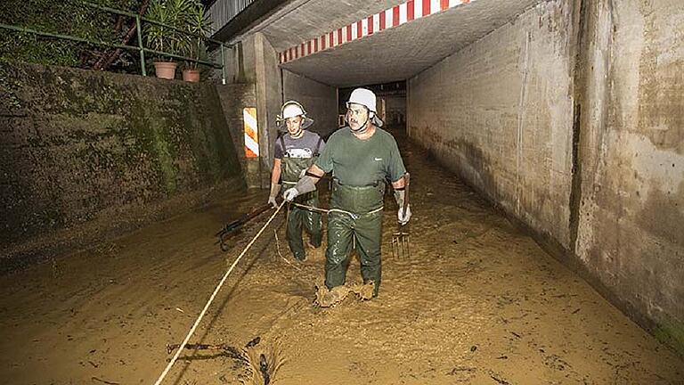 Eine Schlammflut rauschte am Freitagabend durch Gädheim. Die Feuerwehrleute mussten sich sichern, um nicht mitgerissen zu werden.