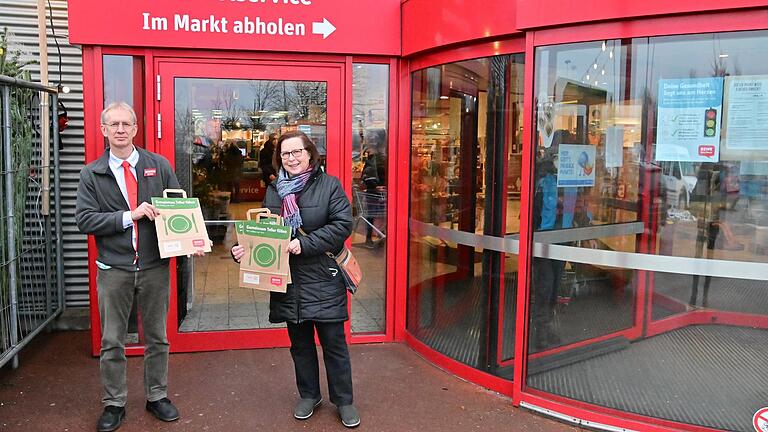 Über 700 solcher Tüten konnten gefüllt mit haltbaren Lebensmitteln vom Rewe-Center an die Tafel Höchberg übergeben werden. Im Bild Centerleiter Marco Gredigk und Magdalena Roßbach, Vorsitzende der Höchberger Tafel.