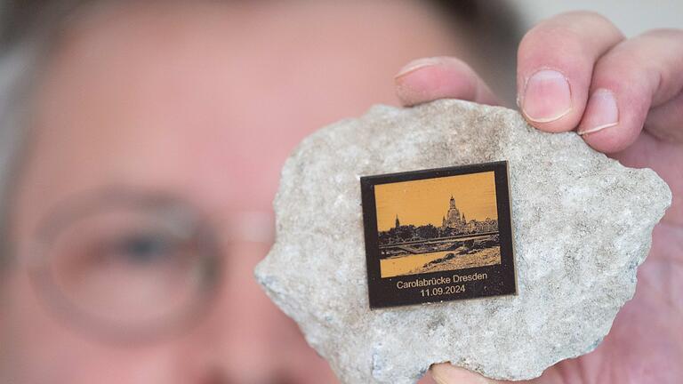 Carolabrücke Dresden - Bruchstücke       -  Torsten Daae, Geschäftsführer im Dresdner Laden &bdquo;Catapult&rdquo;, hält einen Stein des abgerissenen Brückenteils der eingestürzten Carolabrücke mit einer Plakette in der Hand.