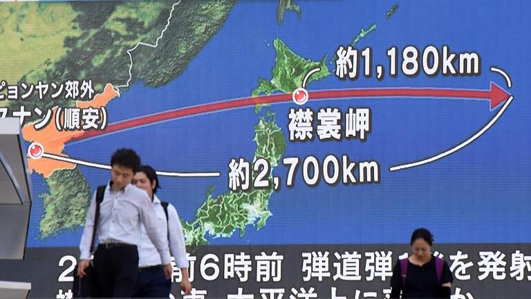 TOPSHOT-JAPAN-NKOREA-DEFENCE-MISSILE       -  Menschen in Tokio vor einem riesigen Bildschirm. Der rote Pfeil zeigt die Flugbahn, die die nordkoreanische Rakete über die japanische Insel Hokkaido genommen hat.