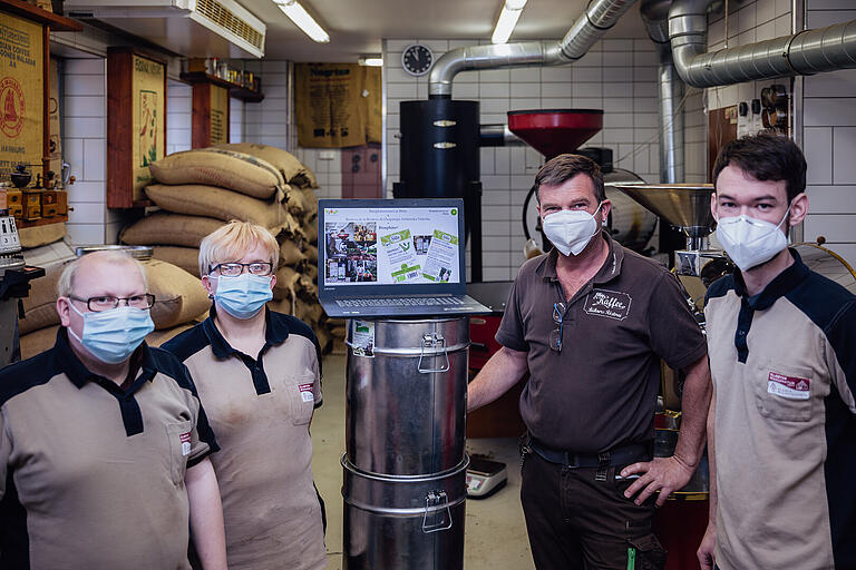 Rainer Bühner (2. von rechts) mit Mitarbeitern in seiner Inklusions-Rösterei in Maria Bildhausen. Gespannt wurde die Videokonferenz zur Unterzeichnung verfolgt.