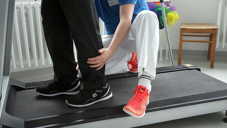Ein Physiotherapeut hilft: Gangschulung auf dem Laufband. Ein Physiotherapeut hilft: Gangschulung auf dem Laufband.