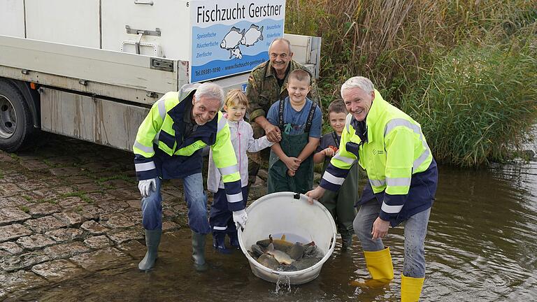 Frische Fische für den Main: Das Foto zeigt Bernhard Kortus (Laborleiter des konventionellen Wasserlabors bei Preußen Elektra), Hanna, Fischerzunft-Obermeister Willi Stein, Ben und Louis, sowie Thomas Fürst (Umweltschutzbeauftragter bei Preußen Elektra) mit einer Ladung Karpfen, die am Grafenrheinfelder Bootsslip in den Main ausgesetzt werden.