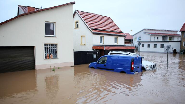 Wasser hat einen Straßenzug mit Autos voll im Griff.jpeg       -  Schäden am Auto durch Elementarereignisse wie Hochwasser sind in der Regel durch die Teilkaskoversicherung abgedeckt.