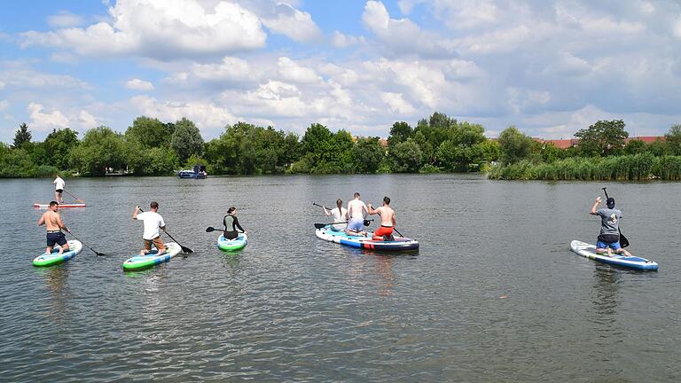 Die kleine Insel umrunden lautet die Aufgabe der SUP-Board-Fahrer und -Fahrerinnen. Die kleine Insel umrunden lautet die Aufgabe der SUP-Board-Fahrer und -Fahrerinnen.