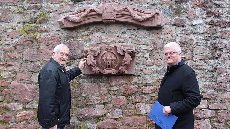 Hubert Schuster (links) und Bruno Schneider (rechts)  an der Stadtmauer vor den gesicherten historischen Bauteilen von Alt-Gemünden.