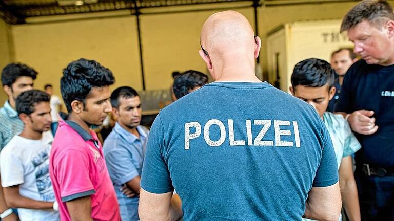 Registrierungsstelle in Passau       -  Andrang in Passau: Polizisten verteilen Flüchtlinge zur Weiterfahrt auf Busse. Verteilen und begleiten, verteilen und begleiten. Das sorgt für Überstunden bei den Beamten.