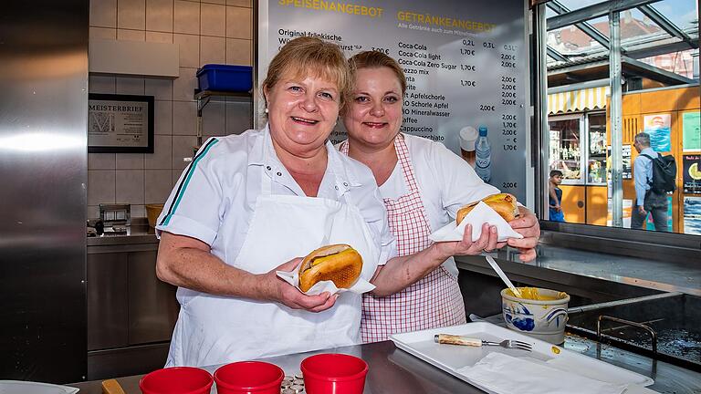 Silvia King (links) und ihre Tochter Charlene King-Demling&nbsp;mit den letzten zwei 'Geknickte mit' der Familie Knüpfing. Am Samstag verkauften sie ein letztes Mal ihre beliebten Bratwürste auf dem Würzburger Marktplatz.&nbsp;