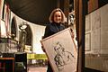 Theaterchefin Angelika Relin im Foyer des Torturmtheaters mit einem Selbstporträt von Veit Relin (1926-2013).