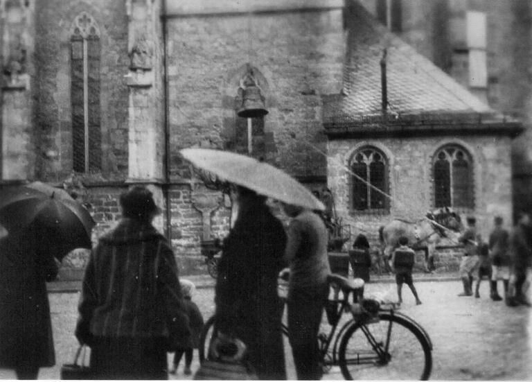 Gerolzhöfer Passanten schauen zu, wie 1942 eine kleinere Glocke aus dem Südturm der Stadtpfarrkirche geholt und auf ein Pferdefuhrwerk geladen wird.