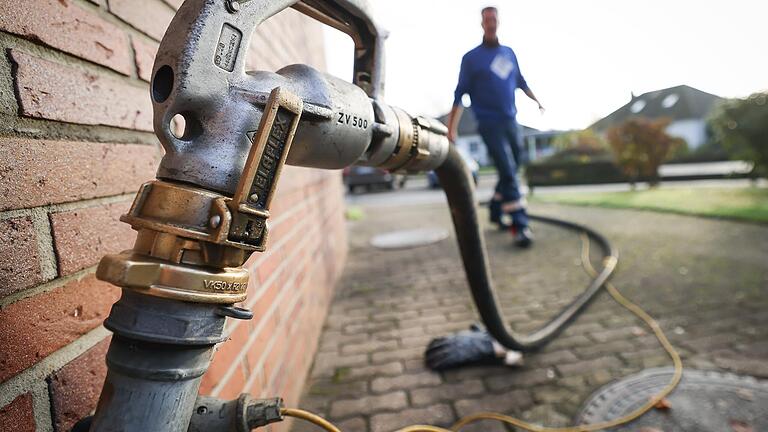 Ein Mitarbeiter eines Diesel- und Heizöl-Unternehmens geht auf diesem Symbolbild zur Zapfpistole an einem Füllstutzen für die Heizöllieferung an einen Kunden in einem Einfamilienhaus. Wer mit Heizöl heizt, kann seit 15. Mai einen Zuschuss zu den Mehrkosten in diesem Winter beantragen.