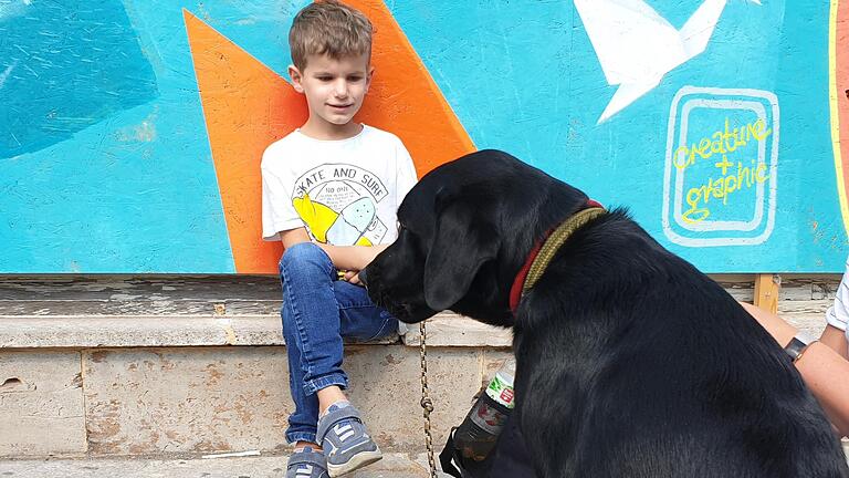 Simon blickt zufrieden auf seinen neuen Weggefährten, einen schwarzen Labrador.