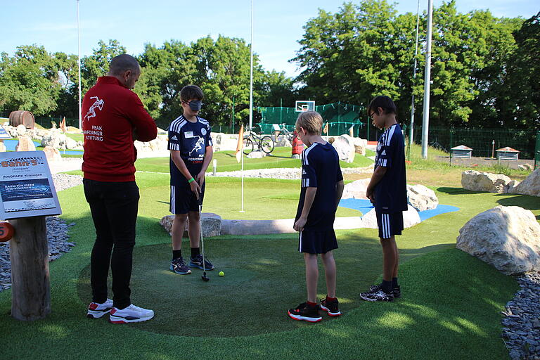 Eine Gruppe Camp-Kinder versucht sich auf dem Minigolfplatz. Für die Variante mit verbundenen Augen braucht es sicher etwas mehr Geduld und Durchhaltevermögen.&nbsp;