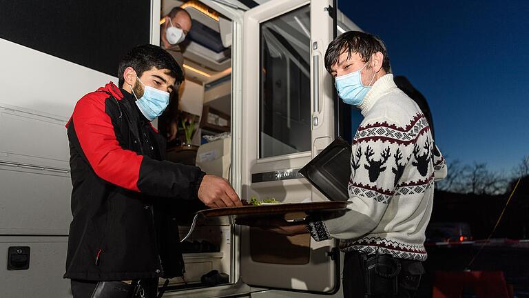 Auszubildende und Mitarbeiter servieren am Abend des Valentinstags vor dem Restaurant des Autohofs in Geiselwind Abendessen – direkt an die Autos und Wohnmobile.