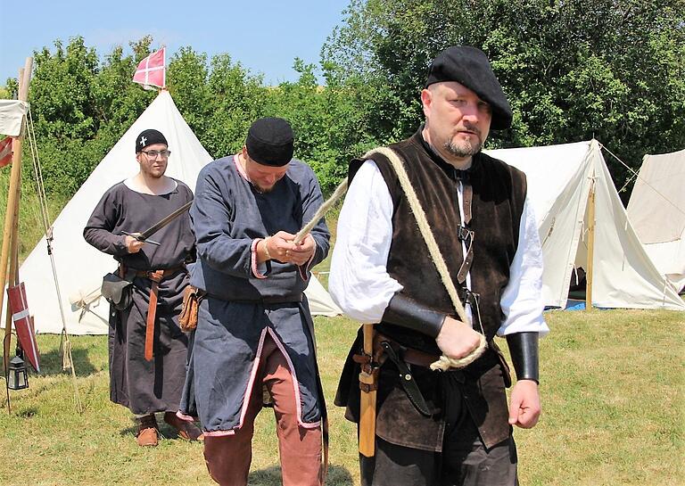 Da wird ein Delinquent abgeführt. Scharfrichter Meister Johannes (Matthias Karl) bringt den des Diebstahls beschuldigten Benedictus von Wengertsbühl (Florian Bergmann) zum Richtplatz. Knappe Patricius (Patrick Stößer) sorgt  dafür, dass der vermeintliche Bösewicht auch schön brav  mitläuft.