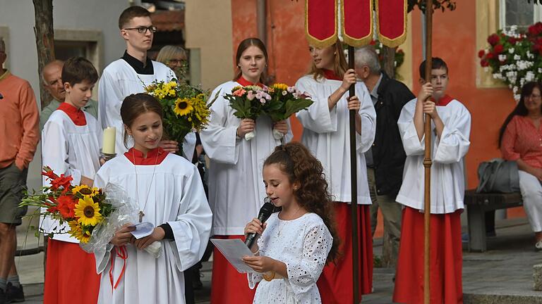 Kommunionkind Lorena Ruhl und ihre Schwester Melina heißen die Wallfahrer vor dem Rathaus mit einem Gedicht und Blumen willkommen.