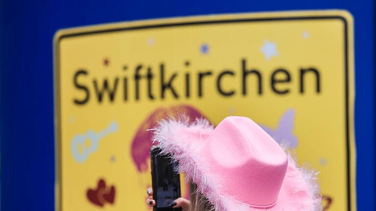 Taylor Swift sorgt für Datenmassen im Handynetz       -  Ein Fan fotografiert vor dem Konzert der Sängerin Taylor Swift in Gelsenkirchen ein &bdquo;Swiftkirchen&rdquo;-Schild. Während des Konzerts am Abend zog der Datenverbrauch in den Handynetzen in der Veltins Arena kräftig an.