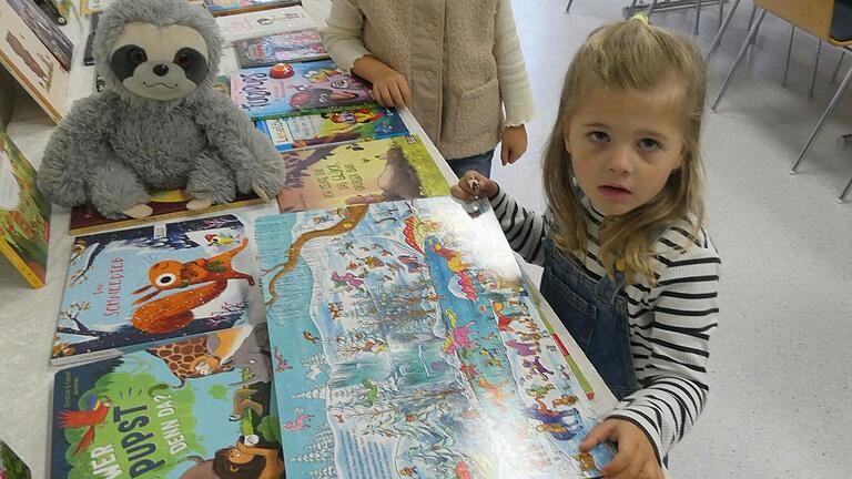 Schon die jüngsten interessieren sich für die neuen Bücher, die die Bücherei ausgestellt hat - wenn der Fotograf nicht ablenkt. Und der beste Freund, der Teddy darf natürlich auch mit in die Bücher schauen.