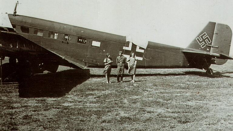 Sonntagsbesuch der 'Tante Ju': Auf dem &bdquo;Fliegerhorst Gerolzhofen&ldquo; genannten Flughafen am Herleshof zwischen Zeilitzheim, Herlheim und dem Gut Wadenbrunn steht um 1941 diese dreimotorige Junkers Ju 52 vor ihrem Abflug nach Afrika, um das Afrikakorps von Erwin Rommel mit Nachschub zu versorgen. Zum Schutz vor Staub und Sonneneinstrahlung sind das Kanzeldach und der MG-Stand in der Mitte mit einem weißen Tuch abgedeckt.