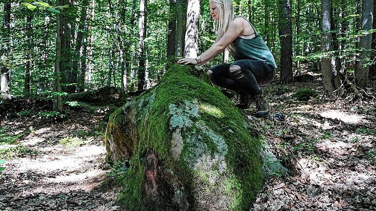 Auf dem Findling mit der Nummer drei legt Spaziergängerin Paulina Heumann ihre Hände auf. Die geomantische Kraft des &bdquo;Heilsteins&ldquo; soll innere Harmonie herstellen.