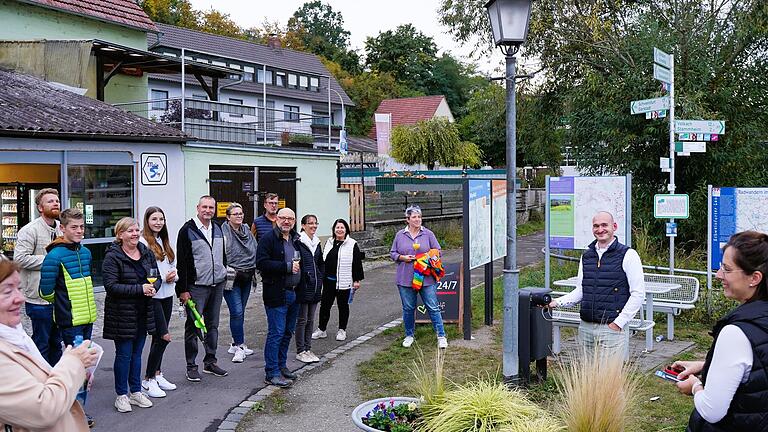 Beim Start des Audiowalks am Fähranleger in Wipfeld: Das Schild mit dem QR-Code hängt am Straßenschild, wie Stefan Volkmuth erläutert. Ganz rechts im Bild: die Umsetzungsbegleiterin der ILE- Region Mainschleife Plus Theresa Ott. Beim Start des Audiowalks am Fähranleger in Wipfeld: Das Schild mit dem QR-Code hängt am Straßenschild, wie Stefan Volkmuth erläutert. Ganz rechts im Bild: die Umsetzungsbegleiterin der ILE- Region Mainschleife Plus Theresa Ott.