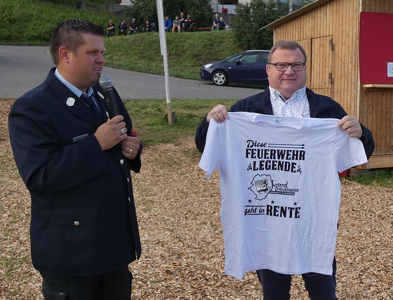 Kreisjugendwart Johannes Krines überreichte Ehren-Kreisbrandinspektor Peter Pfaff ein originelles T-Shirt als Dank für sein jahrzehntelange Engagement in der Jugendfeuerwehr und beim Zeltlager.