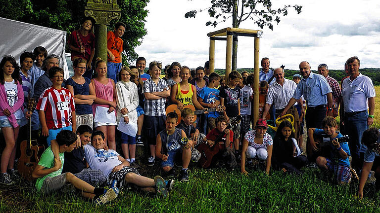 Baumspende: Zwölf Jahre alte Kaiserlinde gepflanzt       -  (hon)  &bdquo;Der Baum ist ein Lebens- und Rohstoffspender. Er spendet Sauerstoff, Schatten, das Farbenspiel und Holz&ldquo;, so Bürgermeister Burkard Losert beim Rimparer Tag des Baumes. Gefeiert wurde dieser, weil eine Kaiserlinde gepflanzt wurde. Das wurde notwendig, da eine der beiden Sommerlinden, die den Bildstock am Rimparer Wolfskreuz umrahmt hatten, gefällt worden war. An ihre Stelle pflanzten Losert, Alexander Hamberger und Ulrich Meyer von der Firma H&M Gartengestaltung den Baum im Wert von 1000 Euro.  Für die musikalische Umrahmung sorgte die Gitarrengruppe (Leitung: Rektor Reinhard Schlereth) und die Singgruppe (Leitung: Jutta Fuchs und Josef Keller) der Maximilian-Kolbe-Schule.