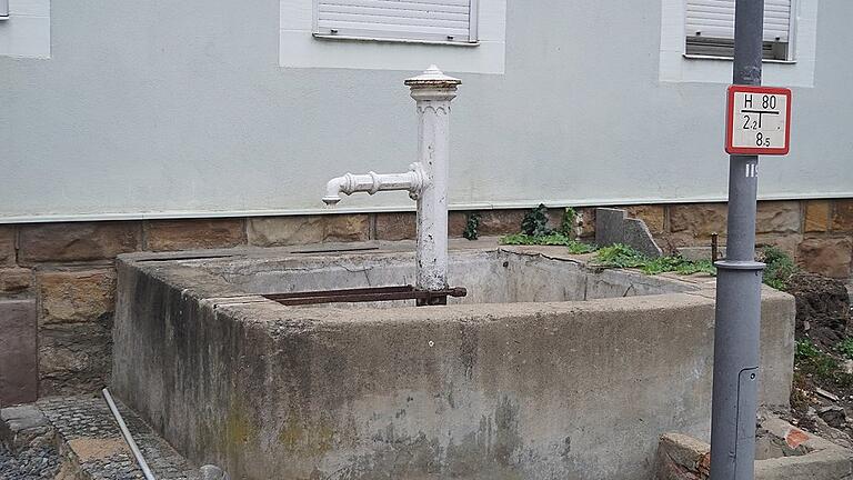 Blick auf den schwer in Mitleidenschaft gezogenen, stillgelegten Brunnen. Er soll abgerissen und durch einen neuen ersetzt werden, die Laterne davor wird ein bisschen versetzt.