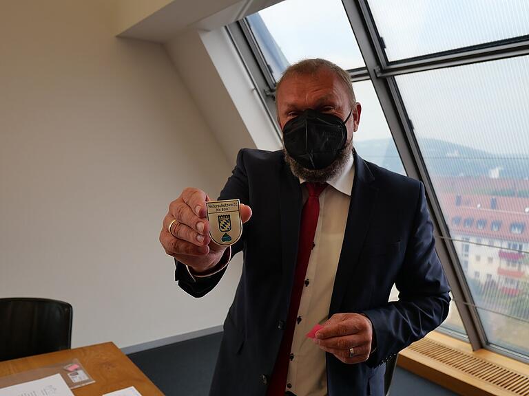 Landrat Thomas Eberth präsentiert die Dienstabzeichen der Naturschutzwächter:innen. Landrat Thomas Eberth präsentiert die Dienstabzeichen der Naturschutzwächter:innen.