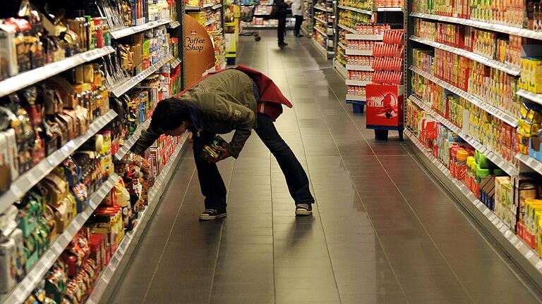 Unten ist es oft günstiger: Eine Kundin greift im Supermarkt nach Bückware im Regal.