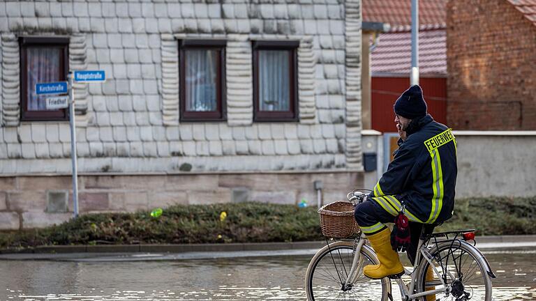 Windehausen.jpeg       -  Ein Feuerwehrmann auf einem Fahrrad in einer überschwemmten Straße in Windehausen.