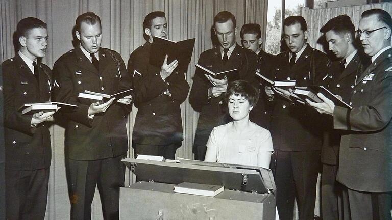 Erika Heim im Jahr 1960 mit dem 'Holy Name Society Choir' im Officers’ Club der Leighton Barracks. Die damals 27-Jährige sitzt an einer Reise-Truhenorgel. 

Foto: Sammlung Erika Heim