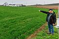 Nur die hellen Stangen im Acker und Messgeräte am Rand (rechts) deuten auf den Versuch hin: Agraringenieur Karl Wieland zeigt auf das Feld am Rand von Güntersleben (Lkr. Würzburg), wo TransnetBW den SuedLink-Betrieb simuliert.