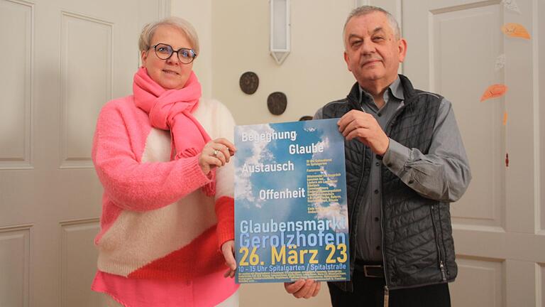 Der Gerolzhöfer Pfarrer Stefan Mai und Anja Iff vom Pfarrgemeindeteam Gerolzhofen halten ein Plakat in Händen für den Glaubensmarkt in Gerolzhofen am 26. März. Dieser lädt unter den Schlagwörtern 'Begegnung, Glaube, Austausch, Offenheit' Menschen jeden Alters und Anschauung zum Austausch und zur Begegnung mit Kirche ein.